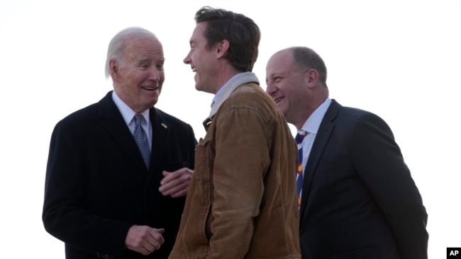 President Joe Biden greets Colorado Gov. Jared Polis, right, and Denver Mayor Mike Johnston as he arrives on Air Force One at Denver International Airport, Nov. 28, 2023, in Denver.
