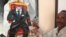 The Somali artist Affey with his painting 'Empty Suit' representing diaspora politicians, Mogadishu, Somalia. (Gabe Joselow/VOA)