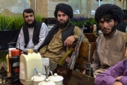 Taliban fighters wait for their meals to be served as they have lunch at a restaurant in Kabul on August 26, 2021. (Wahil Koshar/AFP)