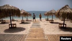 Workers install wooden corridors on a beach, a day before the official opening of beaches to the public following the easing of measures against the spread of the coronavirus disease (COVID-19), in Athens, Greece, May 15, 2020