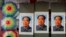 FILE - A salesperson sits near posters of the late communist leader Mao Zedong on display for sale at a shop near Tiananmen Square in Beijing, Sept. 9, 2016.