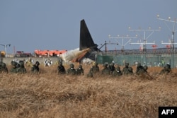 Tentara Korea Selatan mencari penumpang yang hilang di dekat reruntuhan pesawat Boeing 737-800 Jeju Air setelah pesawat itu jatuh dan terbakar di Bandara Internasional Muan di Provinsi Jeolla Selatan, sekitar 288 kilometer barat daya Seoul. (Foto: AFP)