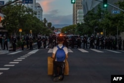 A demonstrator kneels in front of a Police line in Downtown Los Angeles on May 30, 2020 during a protest against the death of George Floyd.