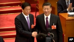 FILE - Chinese President Xi Jinping, right, poses with Li Zhanshu, March 17, 2018, after Li was elected the new chairman of China's National People's Congress (NPC) during a plenary session of the NPC in Beijing. Xi will not attend celebrations of the 70t