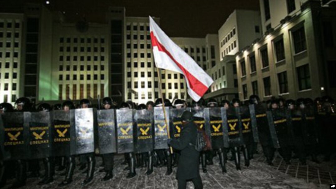 An opposition demonstrator walks in front of the riot police officers during a rally in Minsk, Berlarus, early Monday, Dec. 20, 2010. Thousands of opposition supporters in Belarus tried to storm the main government building to protest what the opposition 