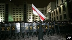 An opposition demonstrator walks in front of the riot police officers during a rally in Minsk, Berlarus, early Monday, Dec. 20, 2010. Thousands of opposition supporters in Belarus tried to storm the main government building to protest what the opposition 