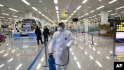 State Commission of Quality Management staff member in protective gear carries a disinfectant pray can as they continue to check the health of travelers and inspect and quarantine goods at the Pyongyang Airport in Pyongyang, North Korea, Feb. 1, 2020.