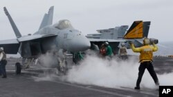 FILE - A flight deck director signals a fighter jet to move on the deck of the nuclear-powered aircraft carrier the USS John C. Stennis, June 15, 2016. 