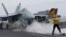 FILE - A flight deck director signals a fighter jet to move on the deck of the nuclear-powered aircraft carrier the USS John C. Stennis, June 15, 2016. 