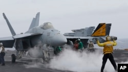 Seorang petugas tengah memberikan tanda kepada pilot pesawa jet tempur untuk bergerak di atas kapal induk USS John C. Stennis, saat latihan militer bersama AS, Jepang dan India di Okinawa, Jepang, 15 Juni 2016. (AP Photo/Shizuo Kambayashi, File)