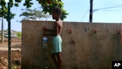 FILE — A boy fills up a bottle at the water fountain in M'tsamoudou, near Bandrele on the French Indian Ocean territory of Mayotte, Thursday Oct. 12, 2023. Water taps flow just one day out of three because of a drawn-out drought compounded by years of water mismanagement.