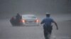 A police officer rushes to help a stranded motorist during Tropical Storm Isaias in Philadelphia, Pennsylvania.