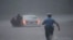 Un policier se précipite pour aider un automobiliste en détresse pendant la tempête tropicale Isaias, le mardi 4 août 2020, à Philadelphie, en Pennsylvanie. (AP Photo/Matt Slocum)