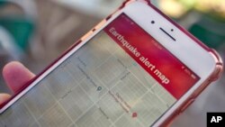 FILE - A mobile phone customer looks at an earthquake warning application on an iPhone in Los Angeles, Jan. 3, 2019.