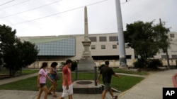  FILE - People walk past the Liberty Place monument in downtown New Orleans, Sept. 2, 2015. In December, the New Orleans City Council voted to remove the obelisk commemorating the Battle of Liberty Place, as well as other Confederate-related statutes.