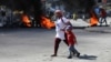 Una mujer y un niño cruzan una barricada en llamas, entre muchas más en varios vecindarios envuelto en la violencia que obliga a los residentes a refugiarse. Puerto Príncipe, Haití, el 18 de enero de 2024.