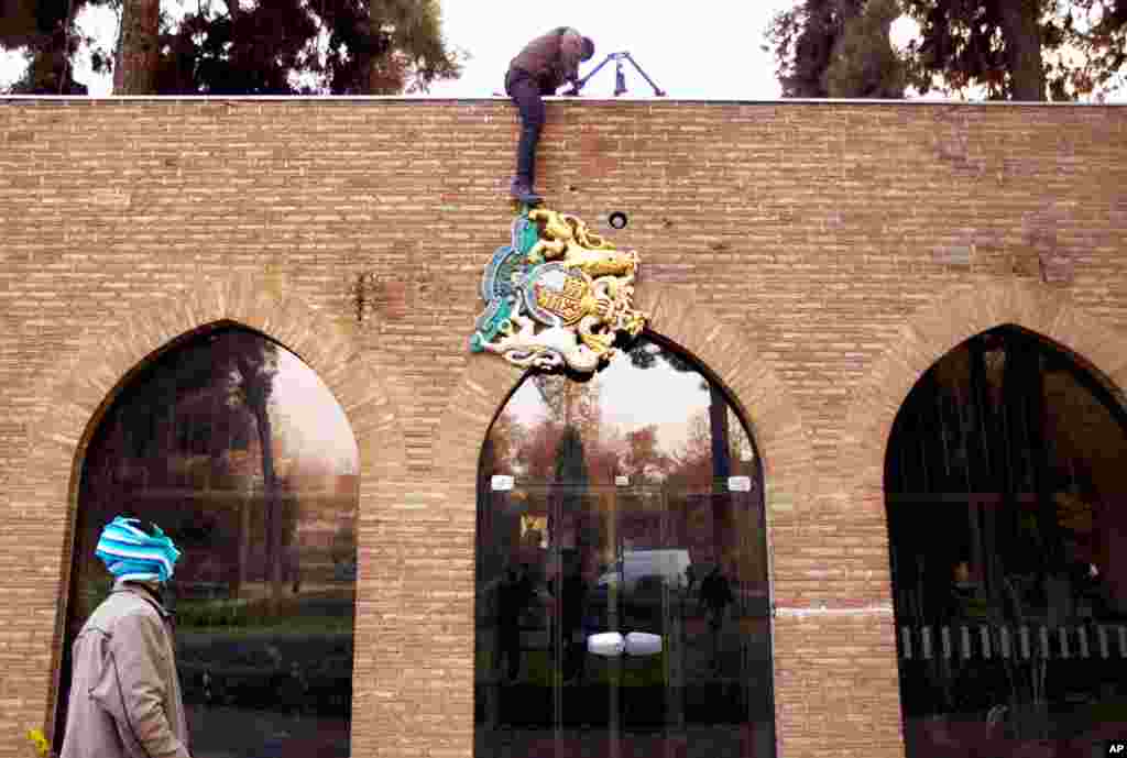 A protesters removes the emblem of the British embassy. (REUTERS/Stringer)