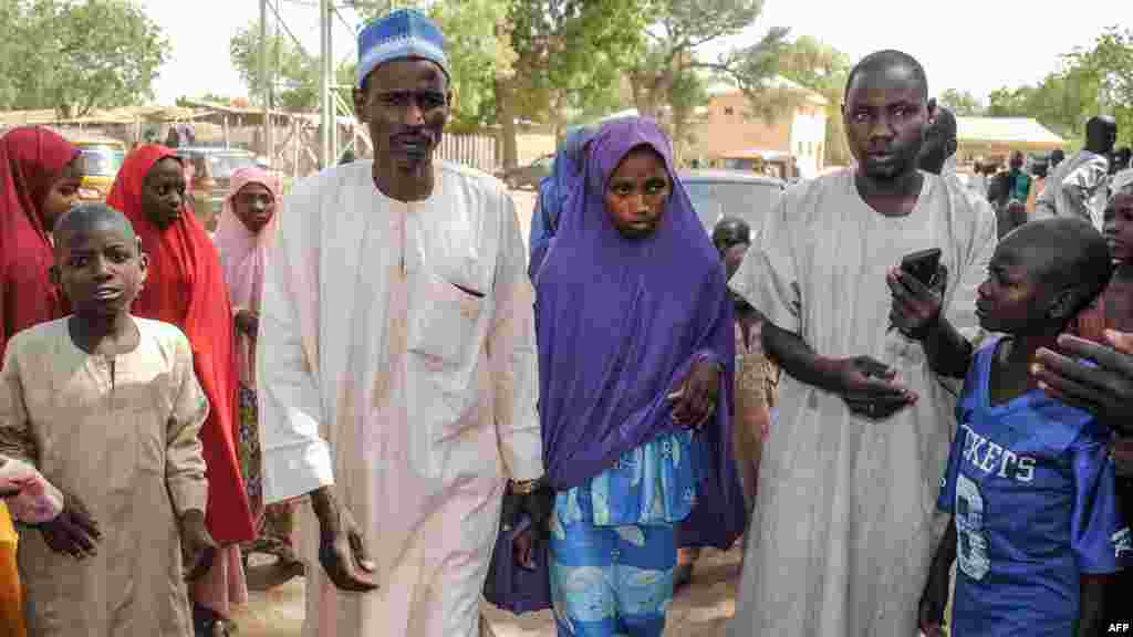 Une fille libérée par Boko Haram marche avec son père à Dapchi apres sa libération par Boko Haram au nord-est du Nigeria, le 21 mars 2018.