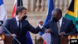 South Africa's President Cyril Ramaphosa, right, bumps elbows with his French counterpart Emmanuel Macron at the end of a joint press conference, in Pretoria, May 28, 2021. 
