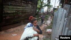 Una mujer protege a su bebé de la lluvia cuando el huracán Iota se acercaba a Puerto Cabezas, Nicaragua, 16 de noviembre de 2020.
