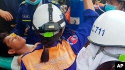 Rescuers carry a survivor from the site of a collapsed building in Preah Sihanouk province, Cambodia, June 24, 2019. 