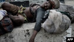 FILE - A homeless woman sleeps under a pedestrian bridge in Port Harcourt, southern Nigeria, Feb. 22, 2019