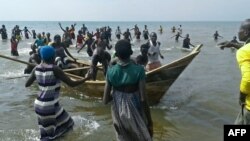 Survivors of a boat accident come back ashore on Lake Albert, Dec. 26, 2016 in Buliisa, after at least 30 Ugandan members of a village football team and their fans drowned when their boat capsized on Lake Albert during a party.
