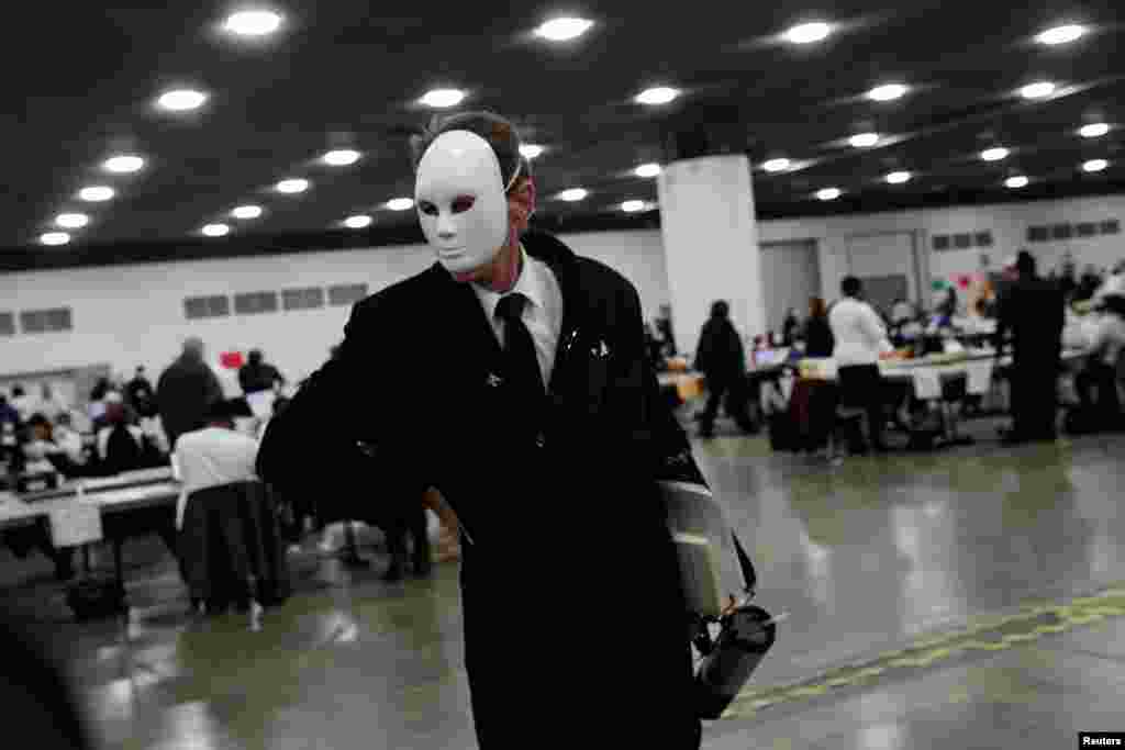 A poll challenger wearing a full face mask reacts while being removed by Detroit Police for causing a disturbance during absentee ballot processing at the TCF Center in Detroit, Michigan.