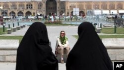 FILE- Iranian women pass a tourist in Isfahan about 400 kms (240 miles) south of Tehran, Iran, May 10, 2006. A U.S. luxury tour company is offering Iran as a new destination.