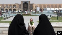  FILE- Iranian women pass a tourist in Isfahan about 400 kms (240 miles) south of Tehran, Iran, May 10, 2006. A U.S. luxury tour company is offering Iran as a new destination.