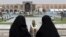  FILE- Iranian women pass a tourist in Isfahan about 400 kms (240 miles) south of Tehran, Iran, May 10, 2006. A U.S. luxury tour company is offering Iran as a new destination.