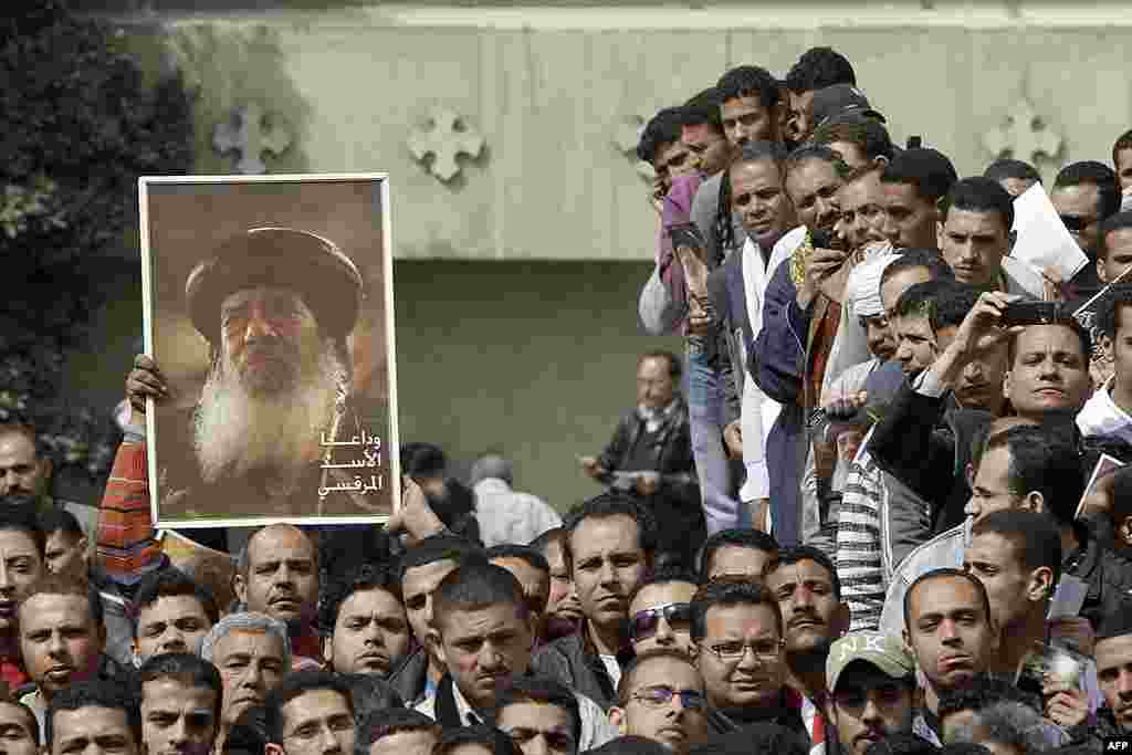 Egyptian Christians watch the funeral of Pope Shenouda, seen in the poster at left, at St. Mark Coptic Orthodox Church in Cairo, March 20, 2012. (AP) 