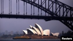 The sun illuminates the Sydney Opera House as a ferry sails past during a storm at Sydney Harbor in Australia, Nov. 23, 2016. 