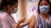 FILE - A woman receives the Pfizer BioNTech vaccine at the Pasteur Institute during a vaccination program, in Paris, Jan. 21, 2021. 