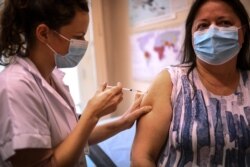 FILE - A woman receives the Pfizer BioNTech vaccine at the Pasteur Institute during a vaccination program, in Paris, Jan. 21, 2021.