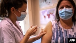 FILE - A woman receives the Pfizer BioNTech vaccine at the Pasteur Institute during a vaccination program, in Paris, Jan. 21, 2021. 