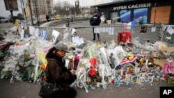 A woman lights a candle outside the kosher grocery where Amedy Coulibaly killed four people in a terror attack, in Paris, Jan. 20, 2015.