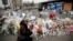 A woman lights a candle outside the kosher grocery where Amedy Coulibaly killed four people in a terror attack, in Paris, Jan. 20, 2015.