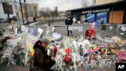 Une femme allume une bougie devant le supermarché juif où le terroriste Amédy Coulibaly a exécuté quatre hommes, à Paris, le 20 janvier 2015.