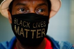 Calvin Stalling, of Atlanta wears a "Black Lives Matter" mask while he waits in a line to vote early at the State Farm Arena on Oct. 12, 2020.