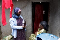 FILE - Fatima Juma, right, receives information on how to prevent the spread of the coronavirus disease from a volunteer of the community organization Shining Hope for Communities in the Kibera slum in Nairobi, Kenya, March 18, 2020.