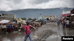 Un vendedor de escobas camina sobre una calle inundada después del paso de la tormenta tropical Isaias en Puerto Príncipe, Haití. 31 de julio de 2020.