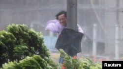 A man holds onto a lamp post against strong winds as Typhoon Hato hits Hong Kong, China, Aug. 23, 2017.