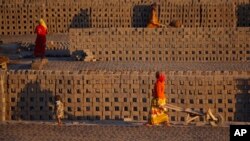 Women laborer transport bricks on hand carts at a brick kiln factory on the outskirts of Jammu, India, Nov. 26, 2013.