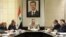 In this undated photo released by the Syrian official news agency SANA on Sunday, Aug. 5, 2012, Syrian Prime Minister Riad Hijab, center, speaks under the portrait of the Syrian President Bashar Assad during a meeting in Damascus, Syria.