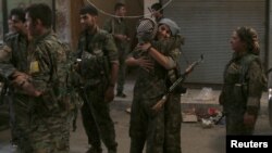 Syria Democratic Forces (SDF) female fighters embrace each other in the city of Manbij, in Aleppo Governorate, Syria, Aug.10, 2016. 