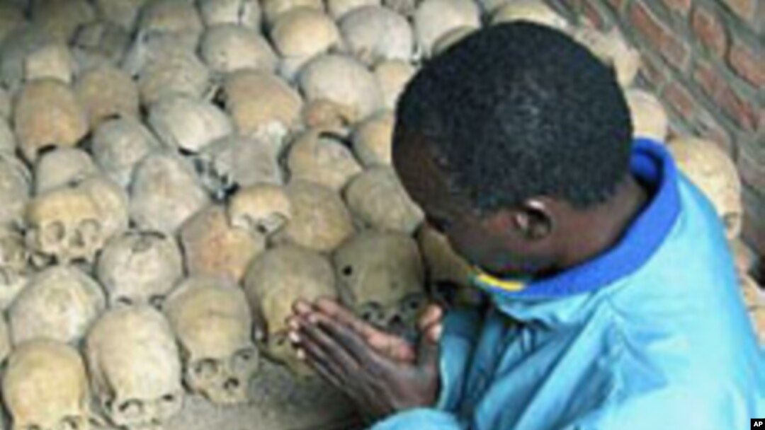 A Rwandan survivor of the 1994 genocide prays over the bones of genocide victims at a mass grave in Nyamata, Rwanda, April 2004. (file photo)
