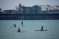 People paddle board backdropped by Brighton Palace Pier on England's south coast, May 30, 2021. The bank holiday weekend and relaxation of England's coronavirus restrictions has enabled many people to visit beaches.