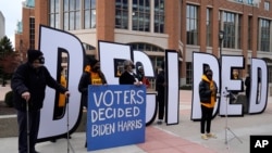 People hold signs outside the Wisconsin Center before a Milwaukee hand recount of presidential votes, in Milwaukee, Wisconsin, Nov. 20, 2020.