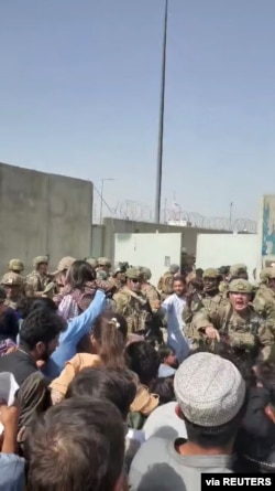 Afghanistan Special Forces try to keep a crowd from entering, outside Kabul Airport, Aug. 18, 2021 in this still image obtained from a social media video.